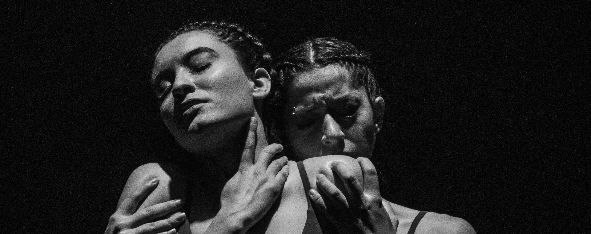 Two women in an expressive, intertwined pose — a dramatic black-and-white still evoking the emotional resonance of the HEAL language